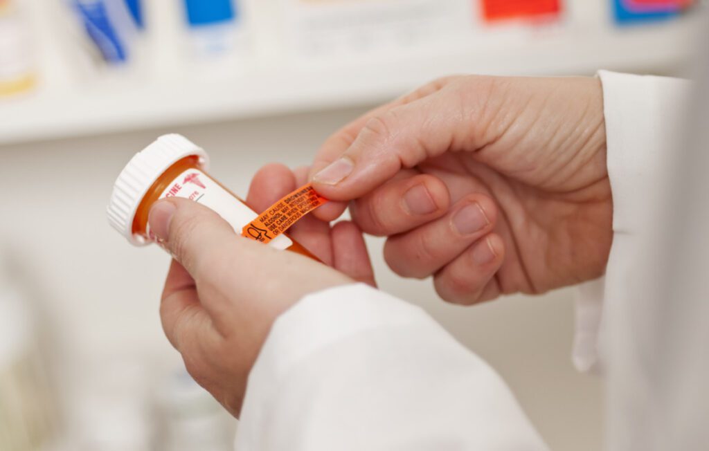 A pharmacist applying clinical trial labels on pill bottle.
